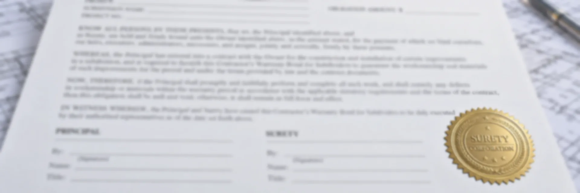A contractor’s warranty bond for subdividers on a desk with subdivision drawings and a gold surety seal, a street of newly built houses behind it — subdivision and development bonds for California